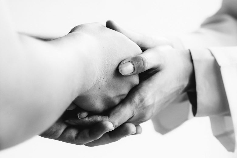 A doctor holds a patient's hand.